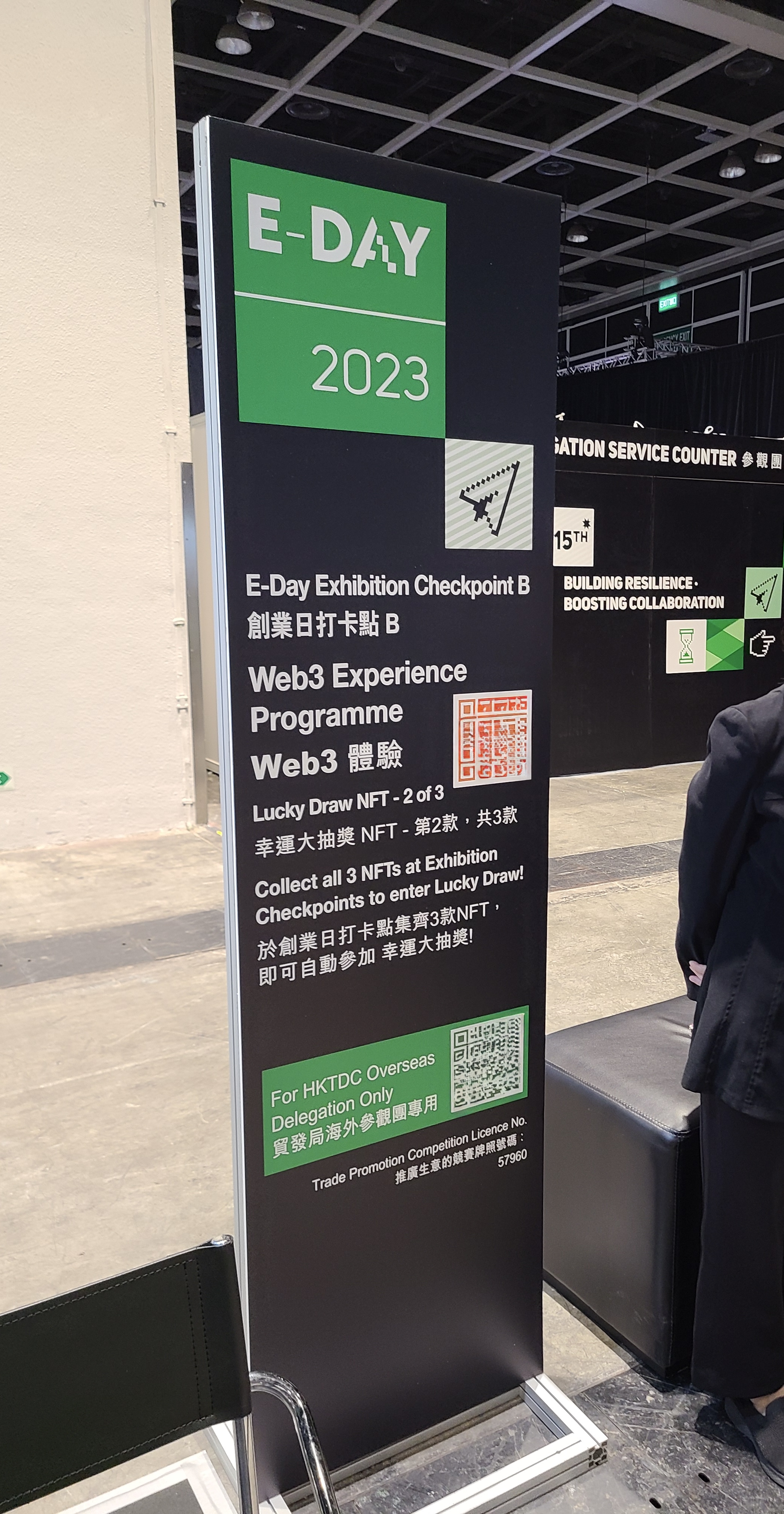 E-Day exhibition checkpoint standee where attendees scan a QR code to collect a lucky-draw NFT